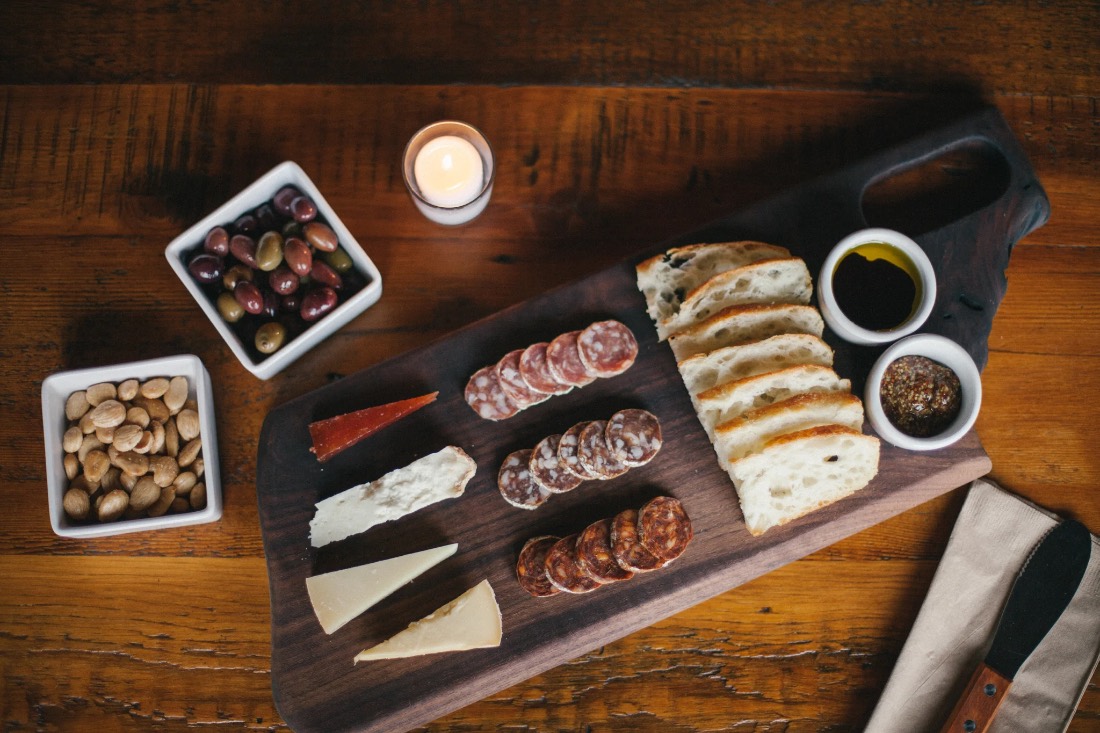 A black-walnut charcuterie board lit by candlelight