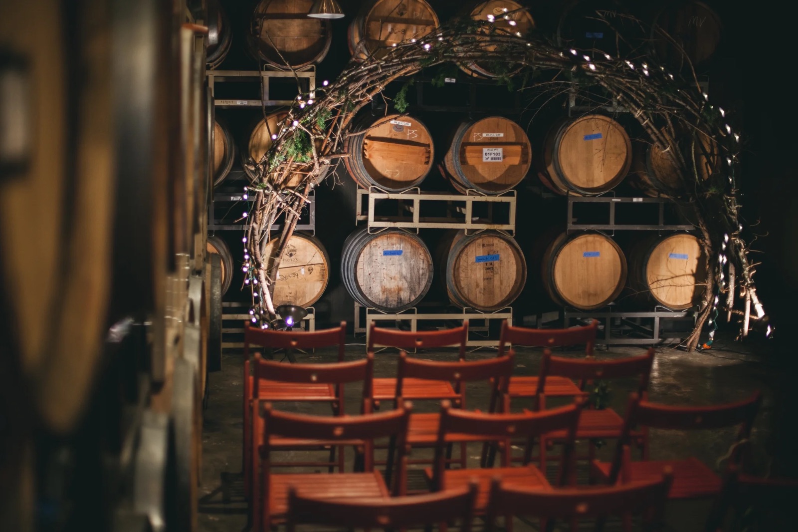 The ENSO Barrel Room set with red chairs and a floral arbor for a ceremony