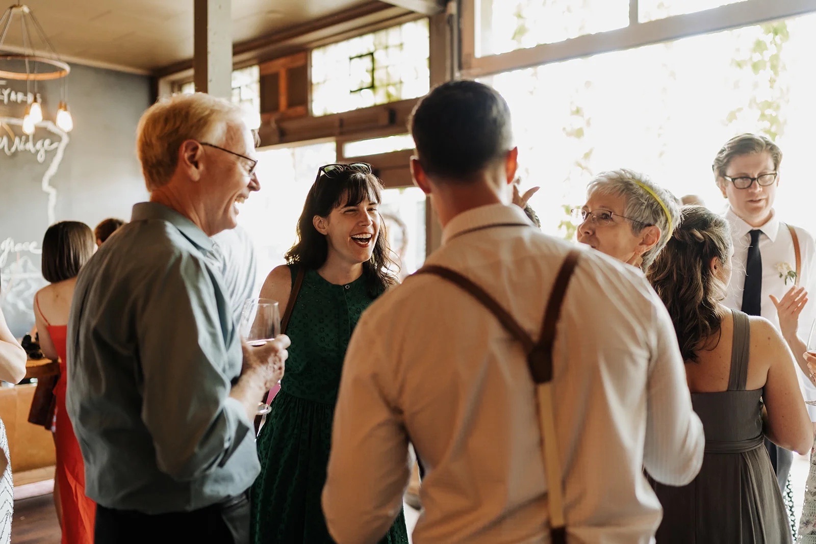 Guests laughing together in the sunlit ENSO lounge during a celebration
