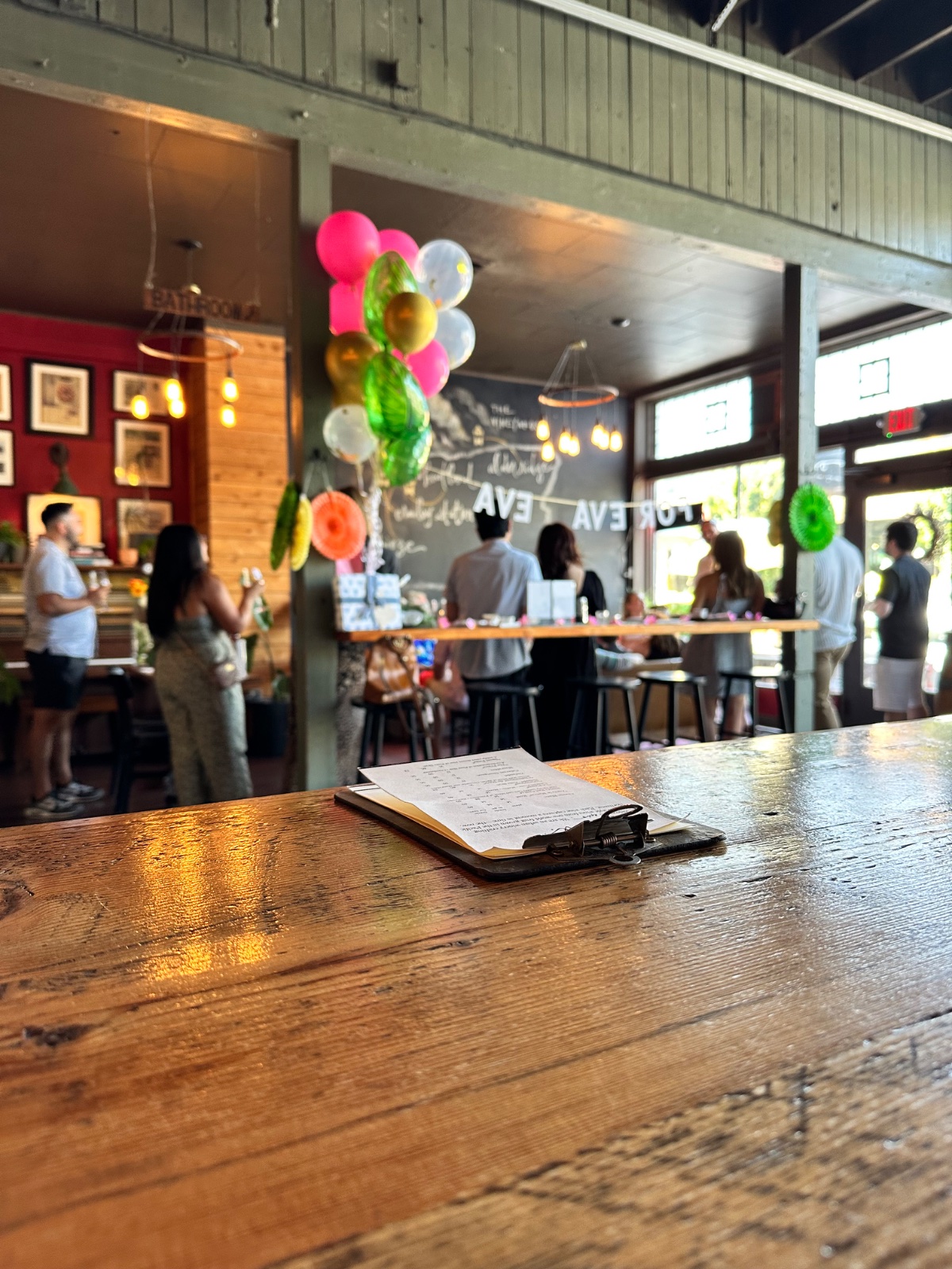 Balloons over the ENSO lounge during a birthday party, the long table set and friends gathered by the windows
