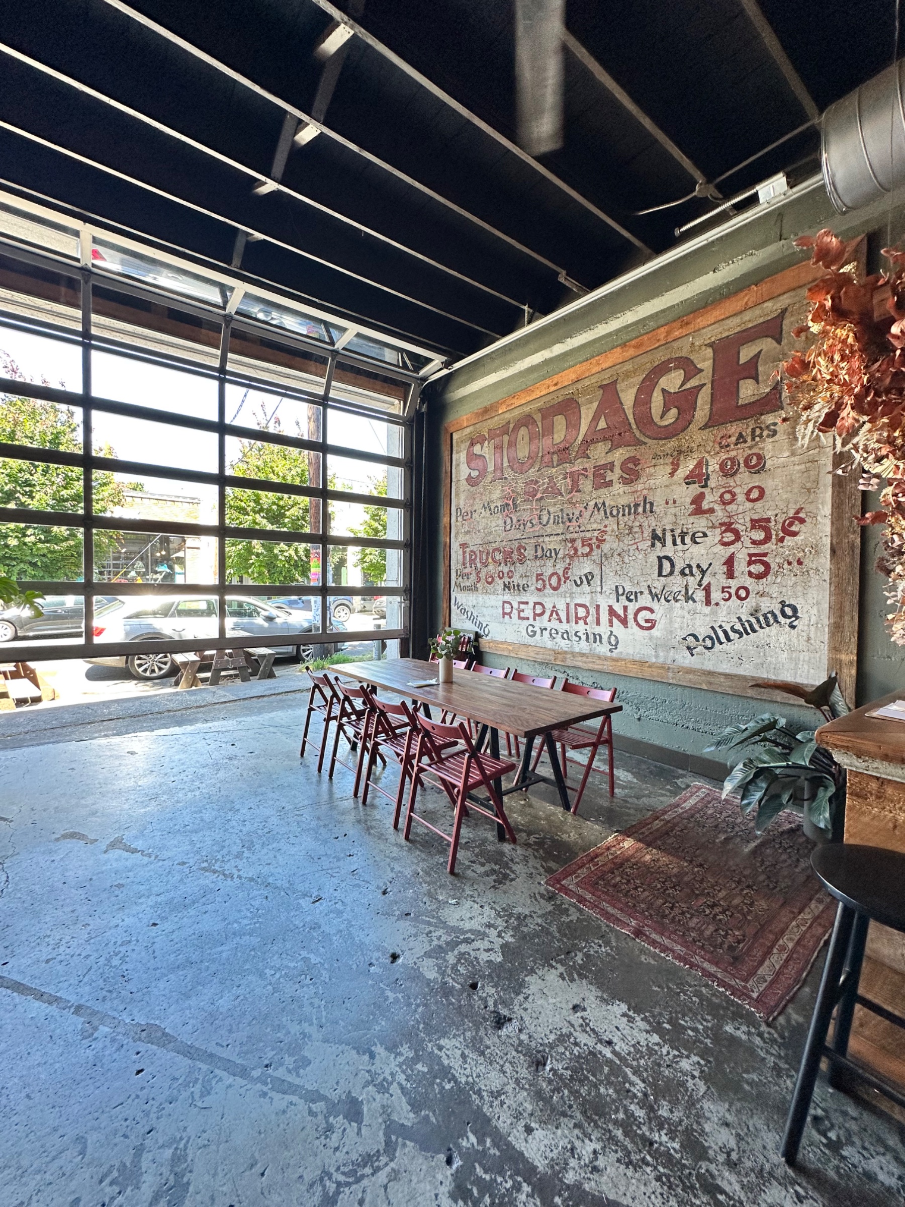 The ENSO space inside the old garage: the original hand-painted Storage Rates mural beside the roll-up door, open to the street