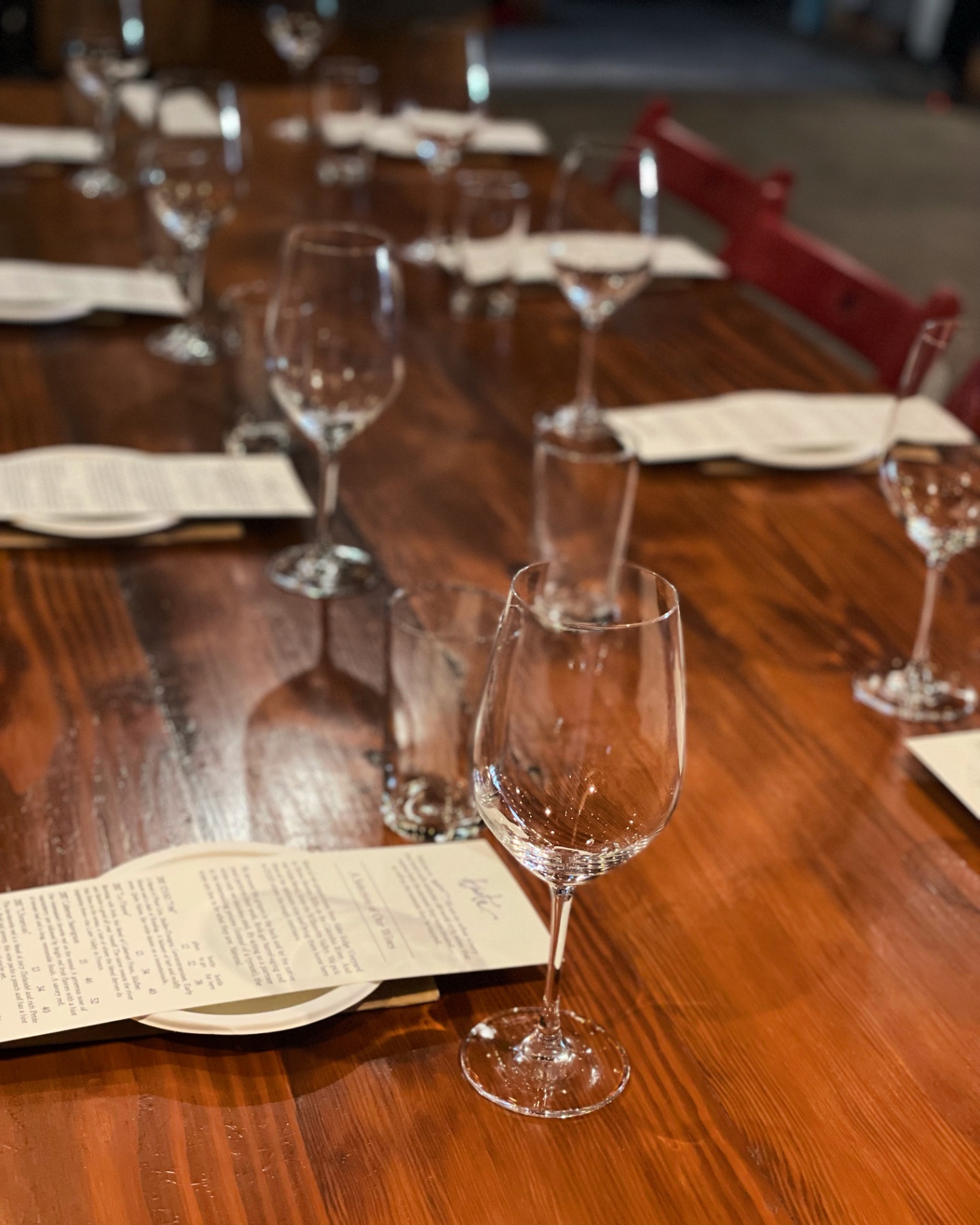 The long farm table set for a private tasting: rows of glasses and printed tasting menus waiting at every seat